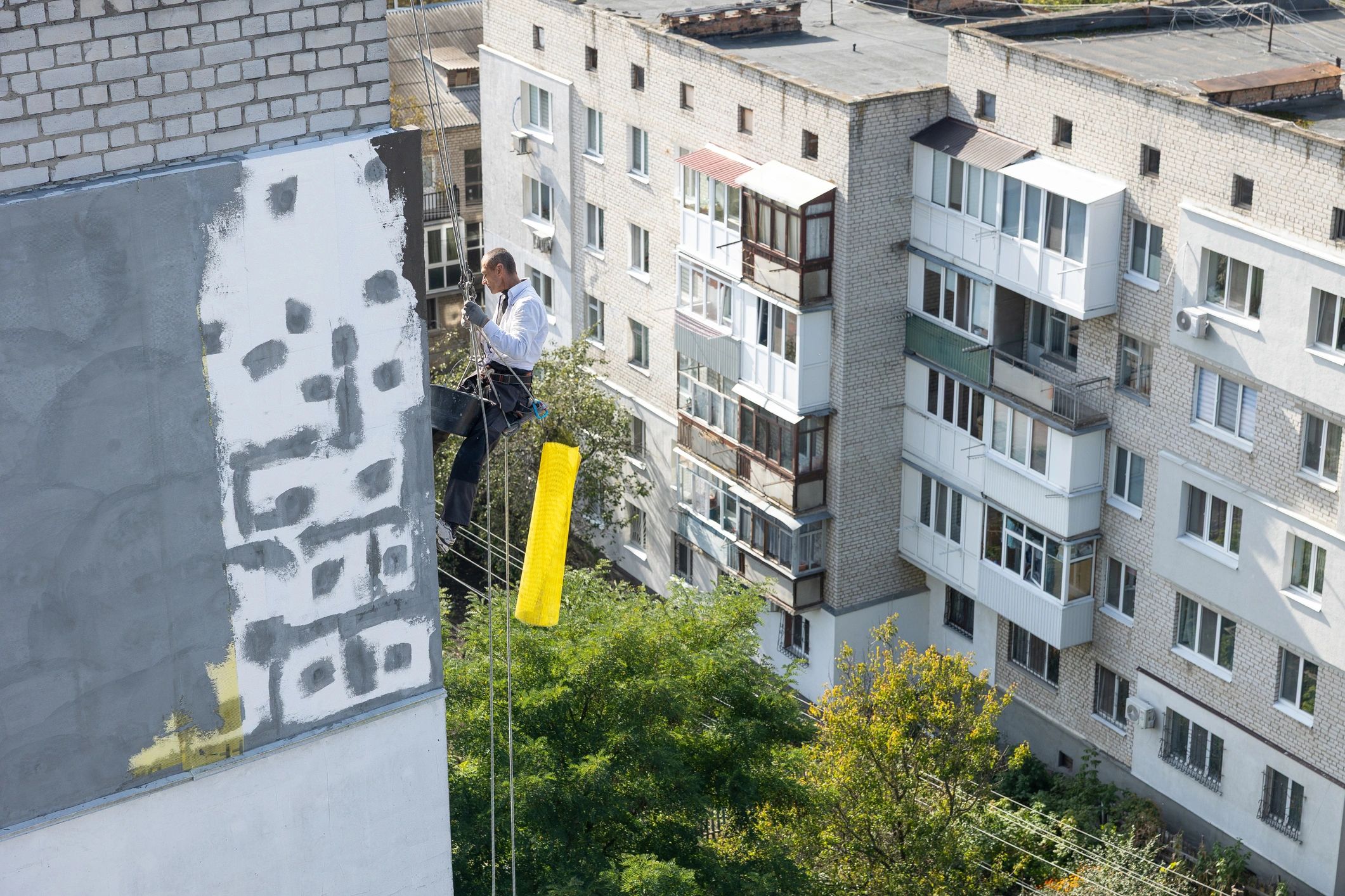 Exterior technician working at height on a commercial building facade